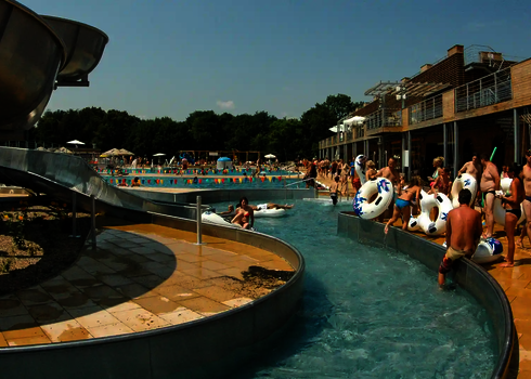 Lazy River mit Rutschreifen, Besuchern und Liegeflächen am Beckenrand.