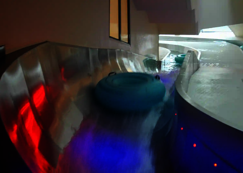 Rutschreifen gleiten durch die Lazy River Wasserrutsche mit bunter Beleuchtung.