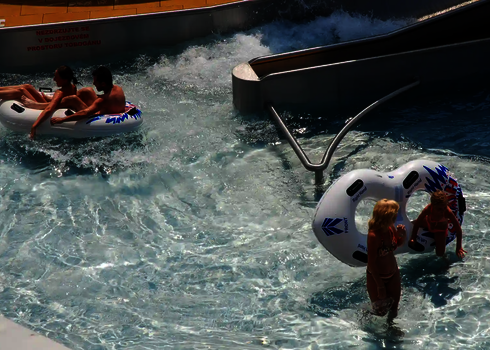 Zwei Kinder und ein Paar nutzen den Lazy River mit Rutschreifen.