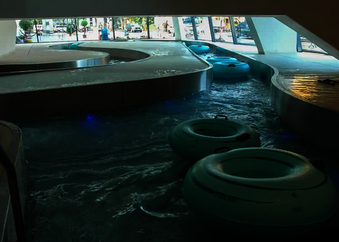 Mehrere Rutschreifen schwimmen im Lazy River mit leicht beleuchtetem Wasser.