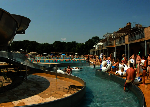 Schwimmbad mit mehreren Badegästen, die sich innerhalb und außerhalb des Lazy Rivers befinden.
